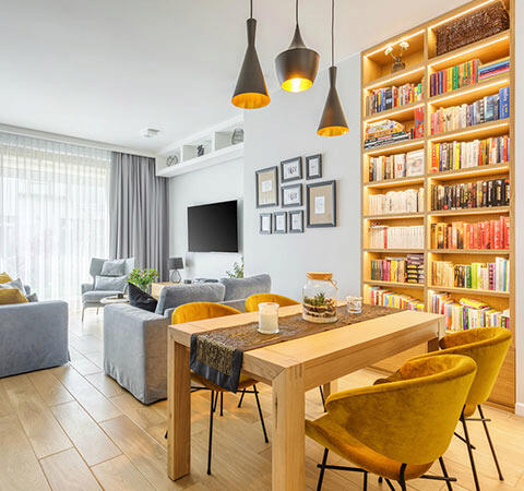 Salon z żółtymi fotelami i regałem na książki, stwarzający przytulną atmosferę do relaksu i czytania.